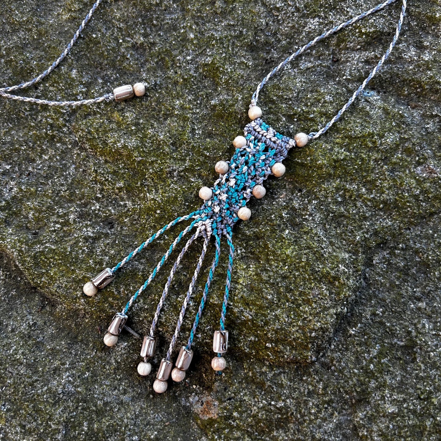 détail collier macramé et perles de bois sur rocher