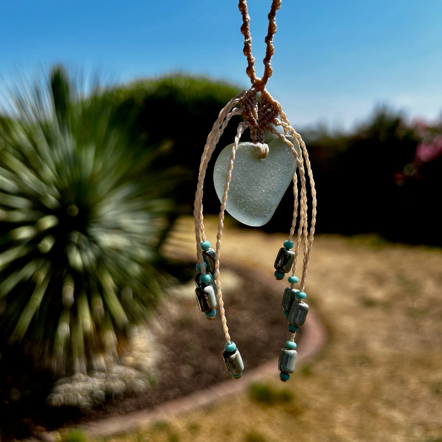 détail pendentif verre de mer fond jardin flouté