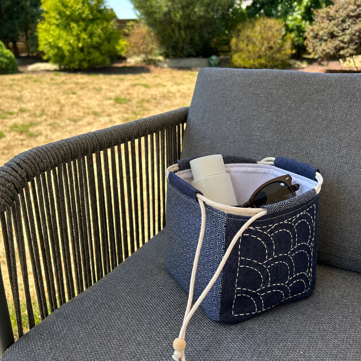 sac japonais brodé posé sur chaise et contenant crème solaire et lunettes