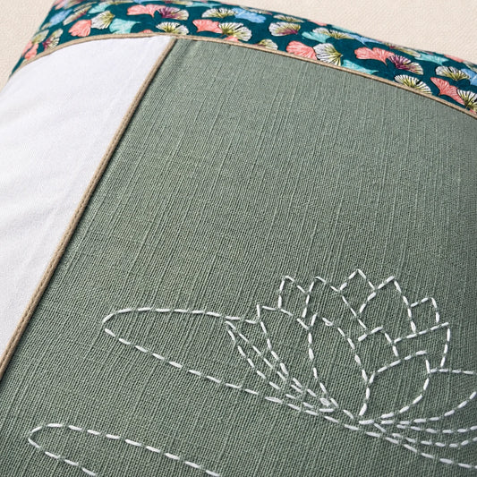 Détail du nénuphar brodé au sashiko blanc sur un coussin en lin vert grisé