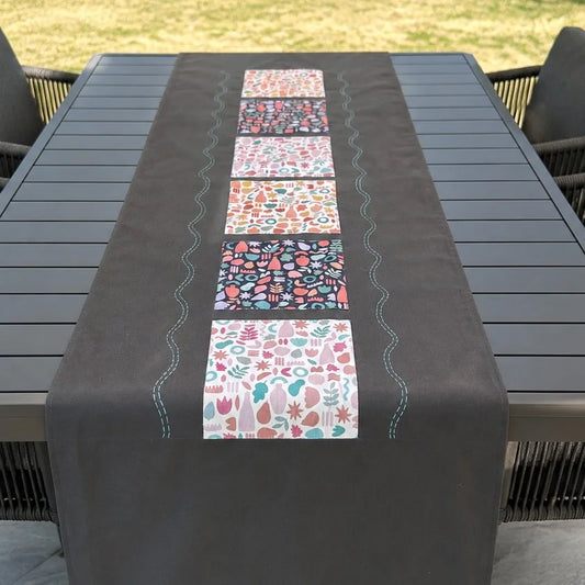 Chemin de table gris avec appliques imprimées carrées présenté sur table de jardin