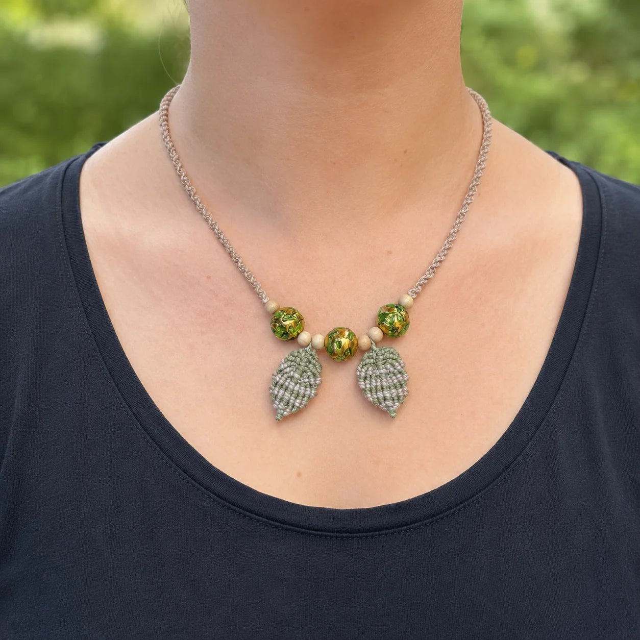 collier macramé et perles de verre vert et or porté par mannequin avec t-shirt noir