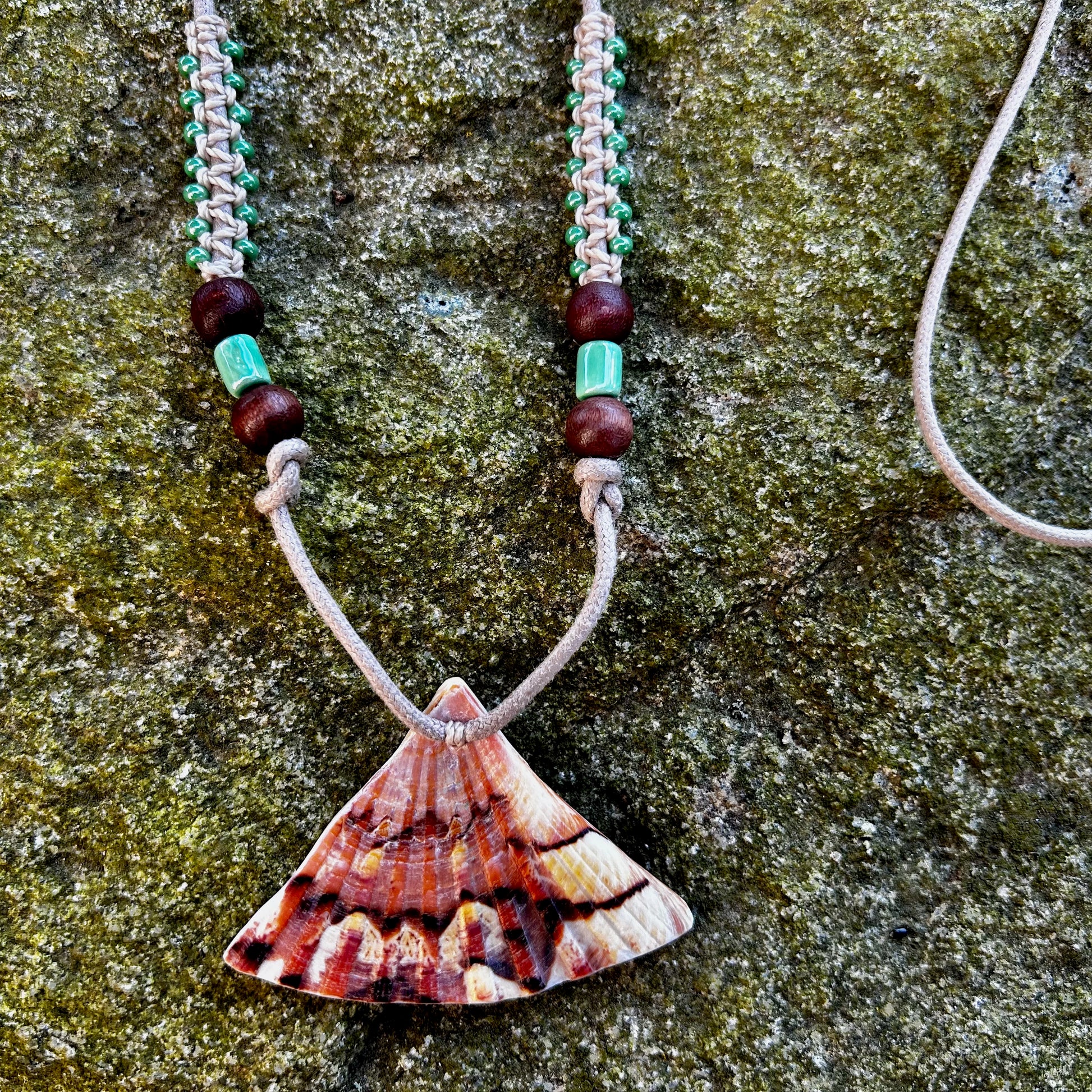 Collier cordon et macramé et coquillage posé sur un rocher