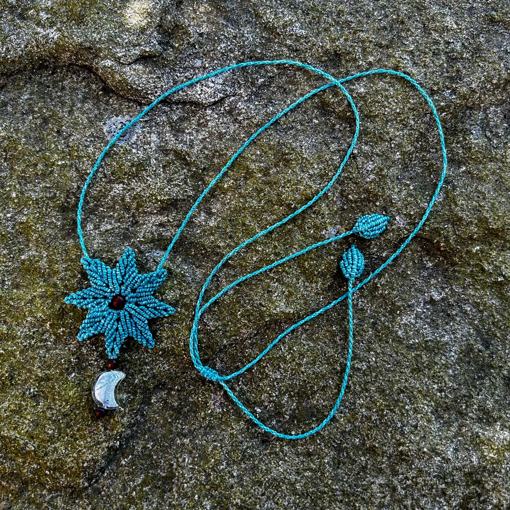 Collier macramé et perle de lune posé sur un rocher