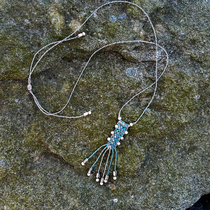 Collier en macramé et perles de bois posé sur un rocher