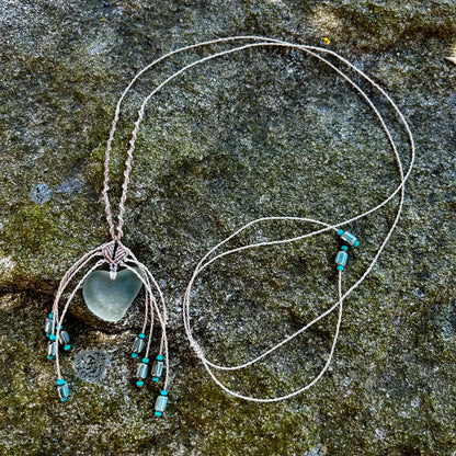 Collier macramé et verre de mer posé sur un rocher