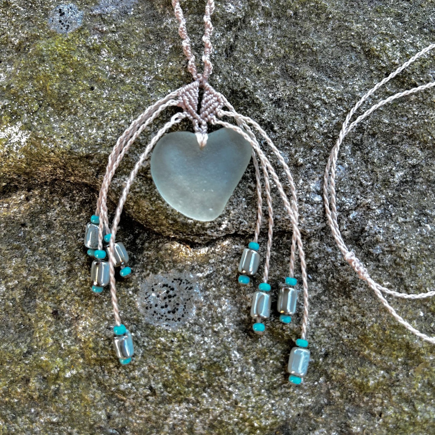 détail pendentif collier en verre de mer posé sur rocher
