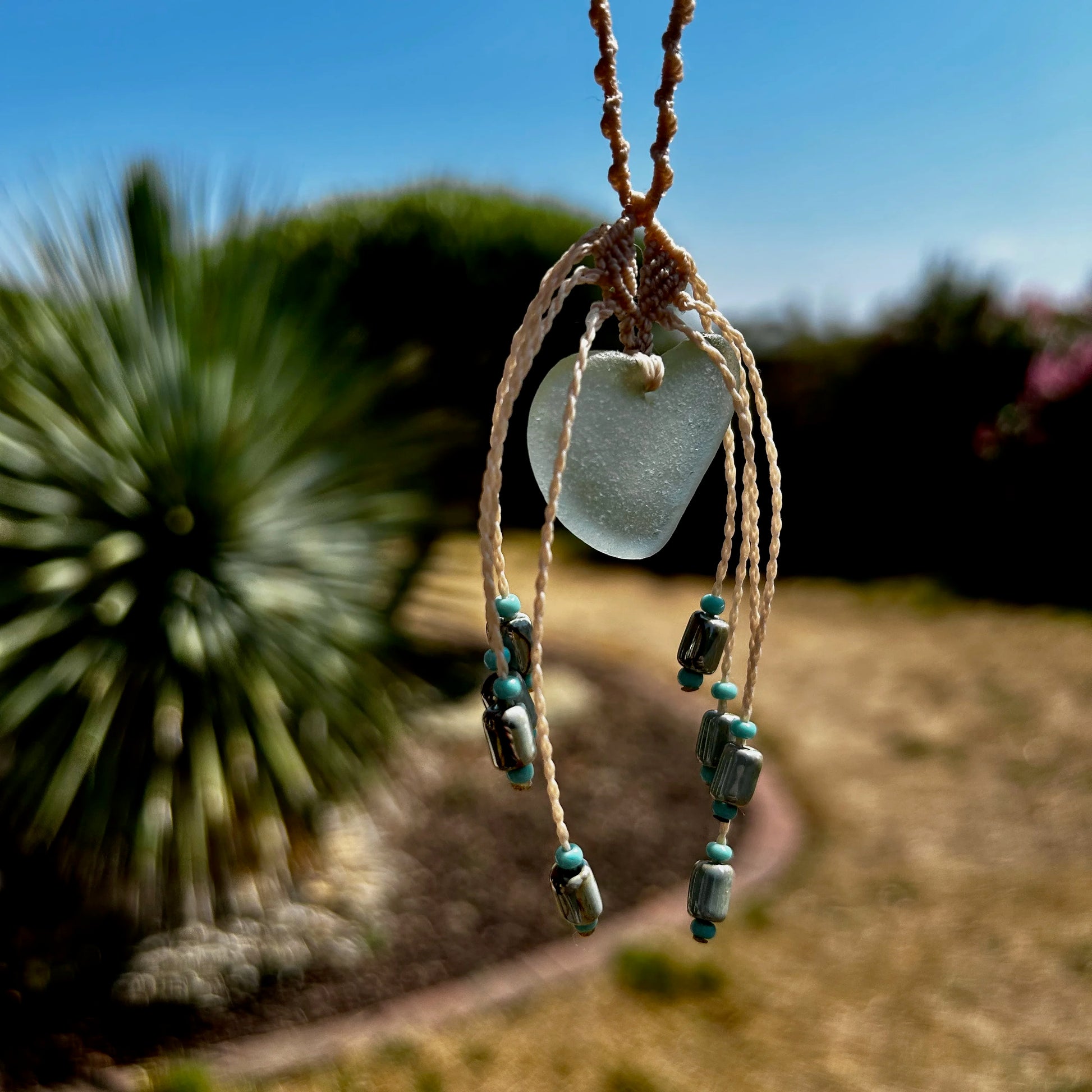 détail pendentif verre de mer fond jardin flouté
