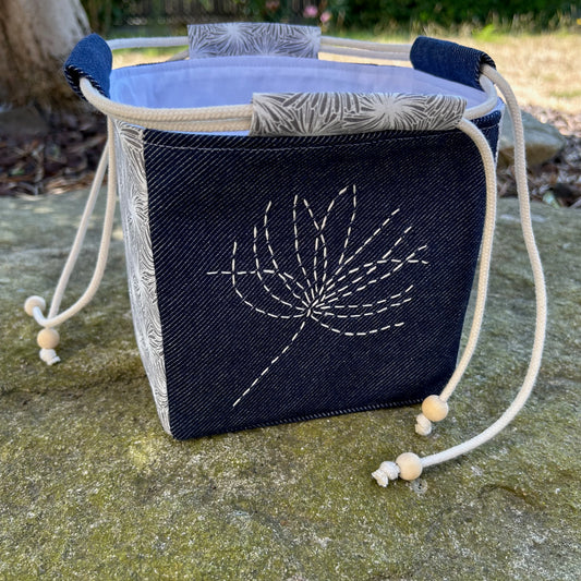 sac japonais brodé d'une fleur posé sur pierre de jardin