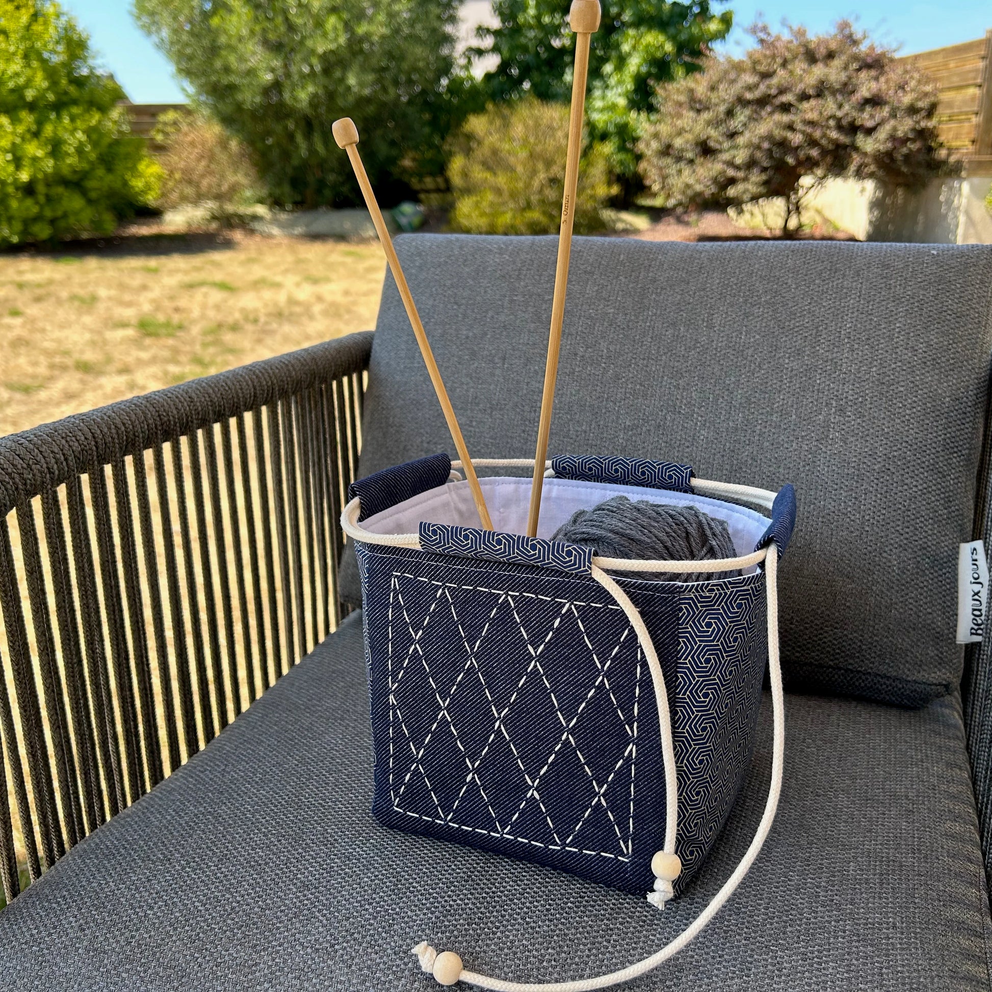 sac japonais brodé posé sur chaise et contenant des pelotes de laine et aiguilles à tricoter