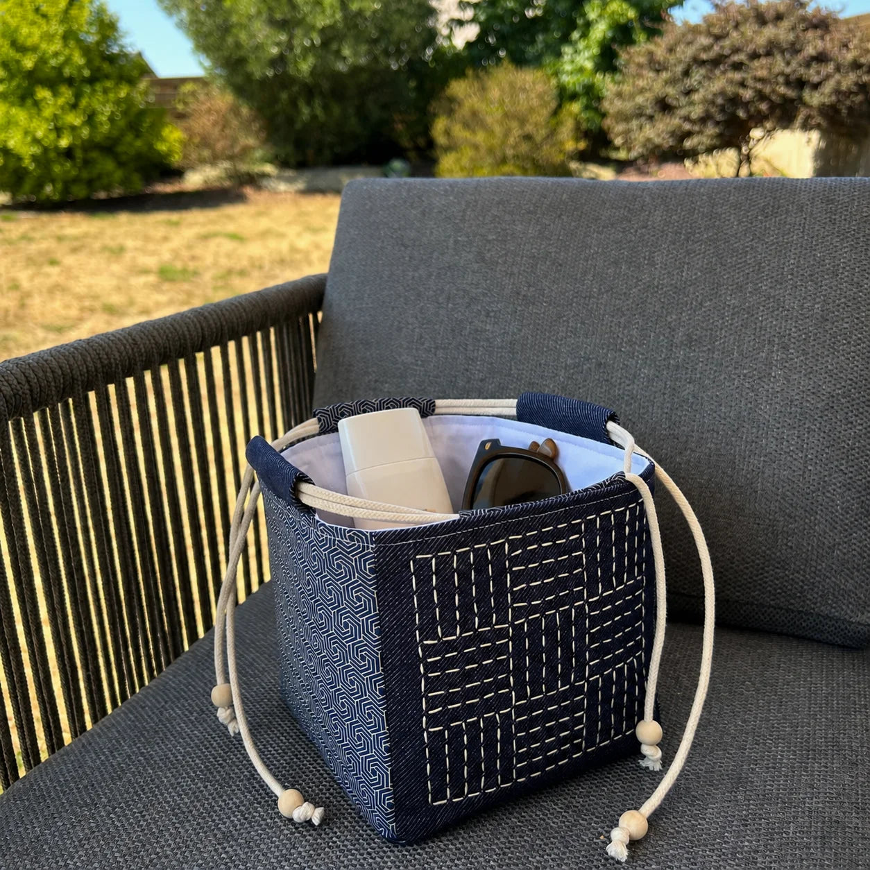 sac japonais posé sur chaise et contenant crème solaire et lunettes