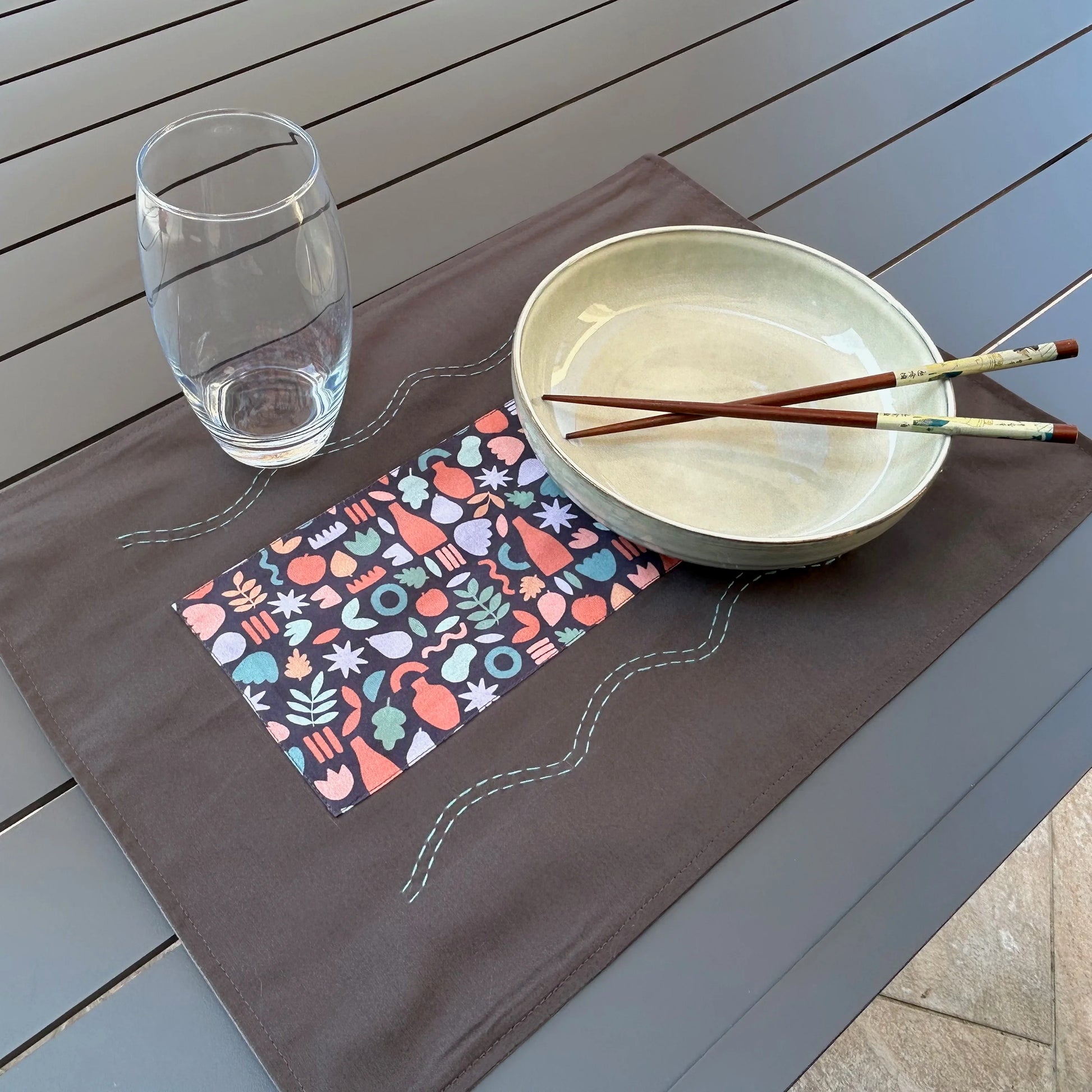 Set de table gris posé sur table avec assiette et verre