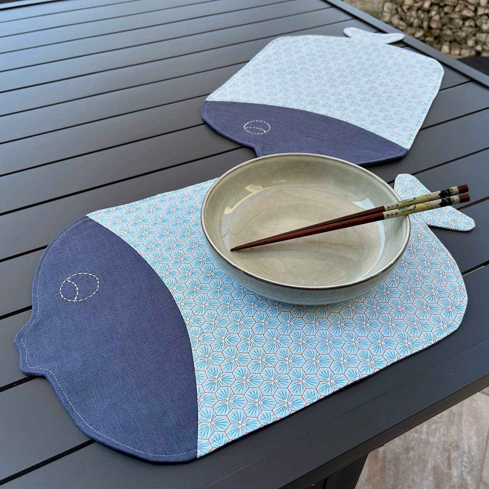 2 sets de table forme poisson bleu présenté en situation avec assiette et verre