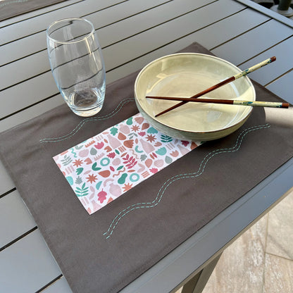 Set de table gris posé sur table avec assiette et verre
