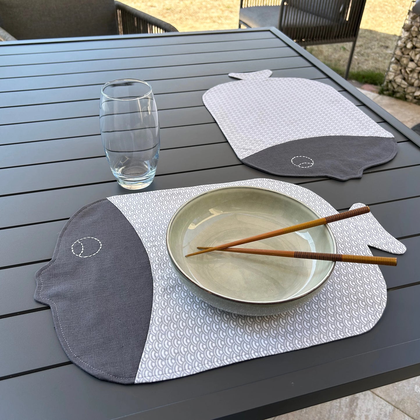 2 sets de table forme poisson gris présenté en situation avec assiette et verre