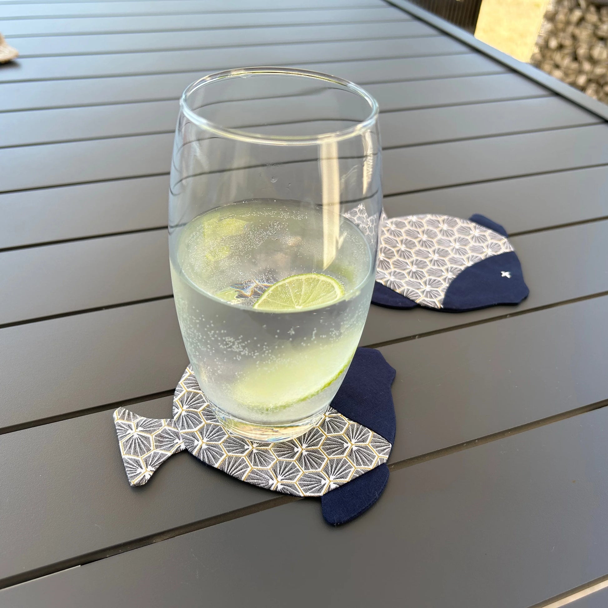 2 sous-verre forme poisson dont l'un avec un verre dessus