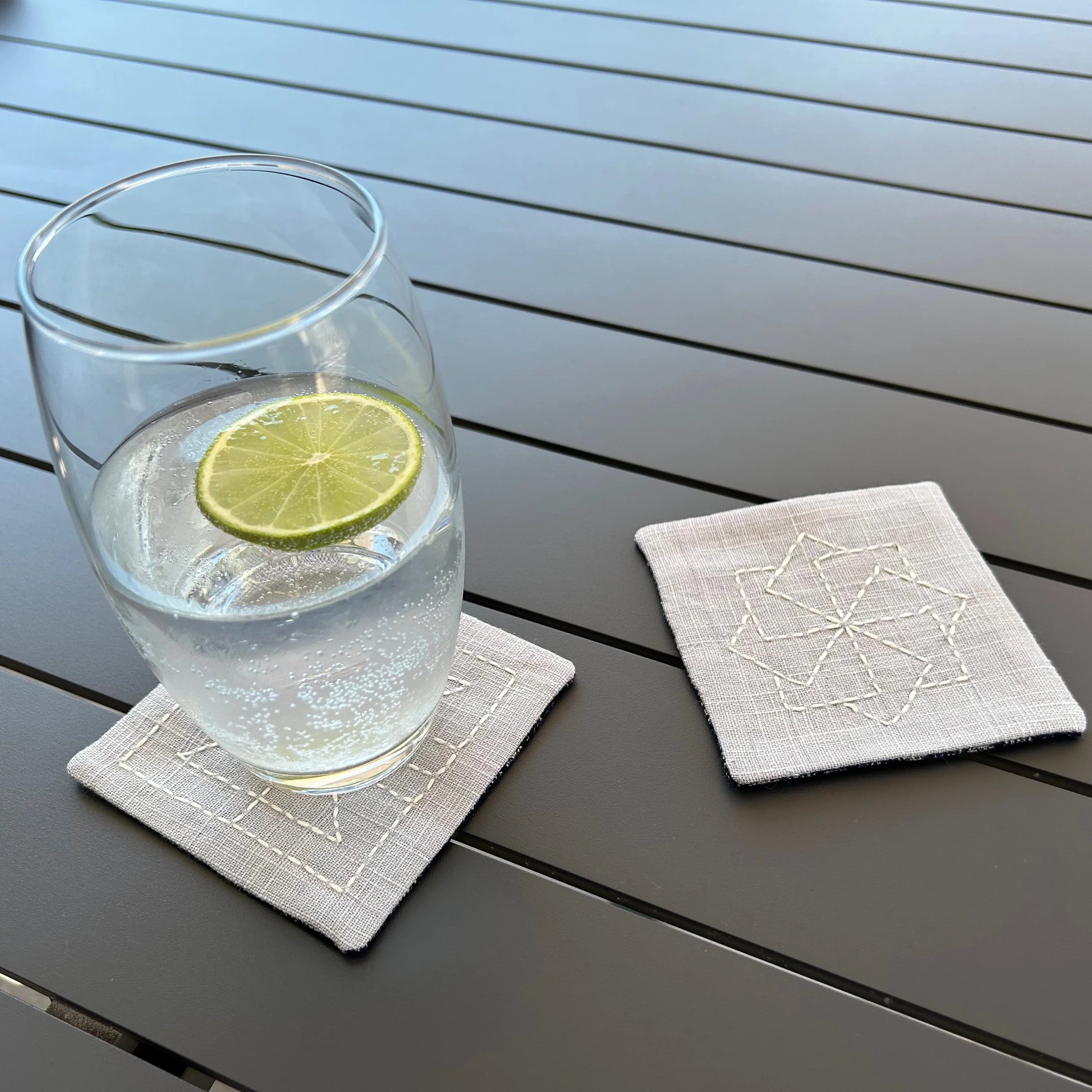 paire de sous-verre brodés sur table avec verre dessus