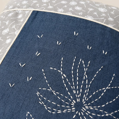 Détail de la broderie sashiko blanche du coussin Fleur de Printemps en lin bleu jean