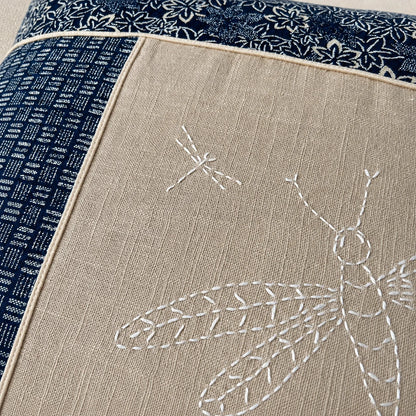 Détail des libellules brodées au sashiko blanc sur le coussin en lin sable et coton japonais